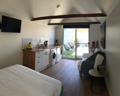 a bedroom with a bed and a kitchen with a sink at Tiny Tom - Hidden beside the river Mersey in Devonport
