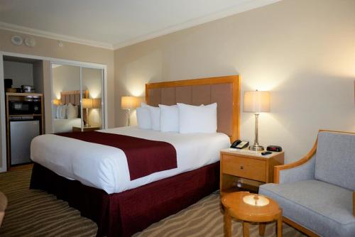 a hotel room with a large bed and a chair at Ocean Sky Hotel & Resort in Fort Lauderdale