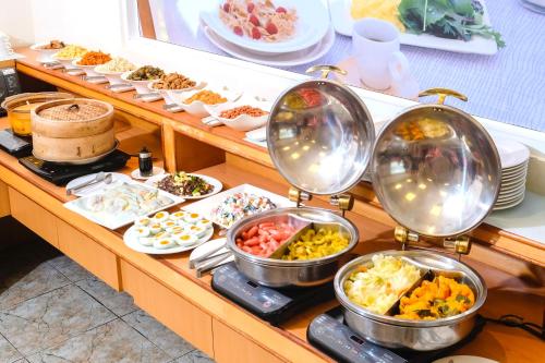 un buffet avec de nombreux types différents de nourriture dans des poêles dans l'établissement Natoli Motel, à Tainan