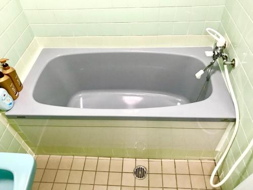 a bath tub in a bathroom with a tiled floor at Miyagi Apartment Tomari in Naha