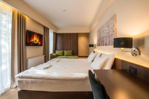Cette chambre comprend deux lits et un bureau. dans l'établissement Hotel Spa Grad, à Kovin