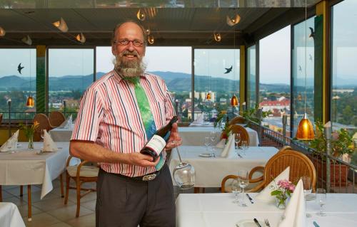 a man holding a bottle of wine in a restaurant at Kapuzinergarten Panoramahotel in Breisach am Rhein