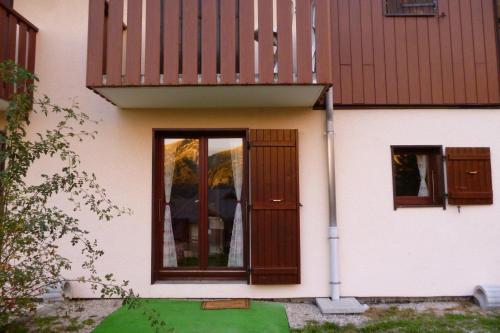 Cette maison dispose d'une porte en bois et d'un balcon. dans l'établissement MONT BLANC SOLEIL E-2, à Manigod