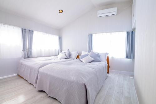 富士河口湖町にあるtocoro. Mt. Fuji 葉月の白いベッドルーム(ベッド2台、窓2つ付)が備わります。