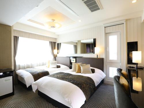 東京にあるアパホテル〈浅草 雷門〉のベッド2台とテレビが備わるホテルルームです。