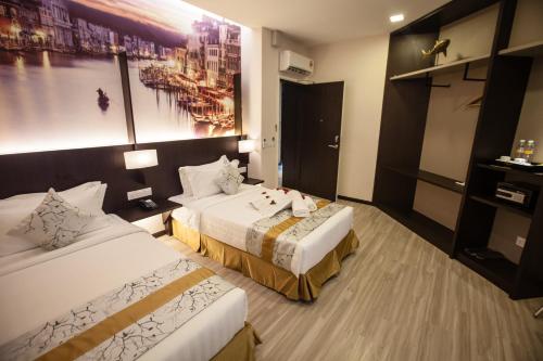 a hotel room with two beds and a painting on the wall at Amamas Boutique Hotel Kuching in Kuching
