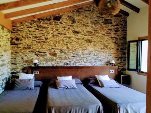 2 camas en una habitación con una pared de ladrillo en Casa Garea, en Arzúa