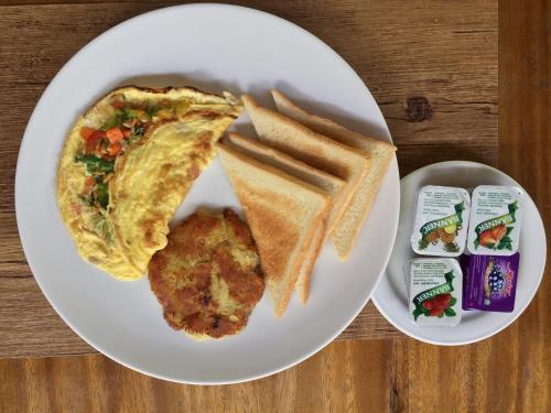 a white plate of food with a omelet and bread at Bali Spirit Hotel and Spa, Ubud in Ubud
