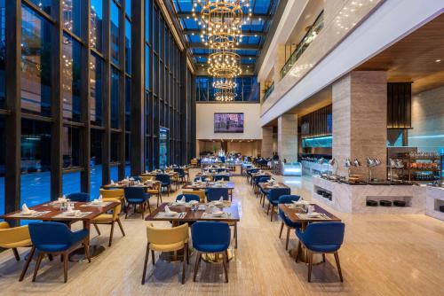 a restaurant with tables and chairs and a chandelier at Novotel Qingdao New Hope in Qingdao