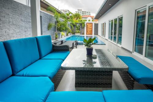 a patio with blue couches and a table and a pool at Majestic by Korawan in Pattaya South