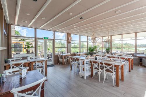 a restaurant with tables and chairs and windows at Hajé Hotel Restaurant de Lepelaar in Lelystad