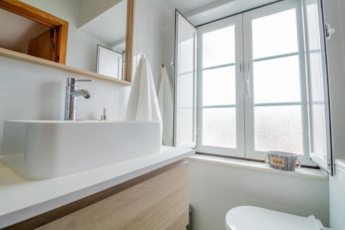 een badkamer met een witte wastafel en een raam bij Belém Sweet Spot in Lissabon