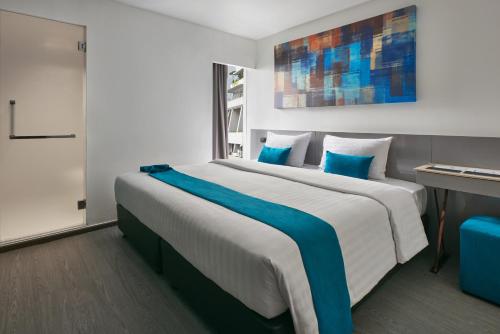 a bedroom with a large bed with blue pillows at Sora Hotel Silom in Bangkok