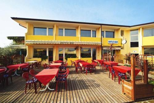 un ristorante con tavoli e sedie rossi su una terrazza di Hotel Centro Turistico Gardesano a Bussolengo