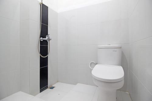 a white bathroom with a toilet and a shower at RedDoorz Plus @ Taman Siswa 3 in Yogyakarta