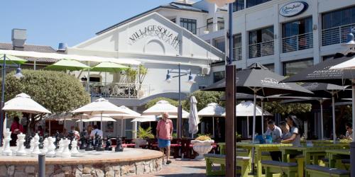 a group of people sitting at tables in front of a building at Zzzone Boutique Hostel in Hermanus