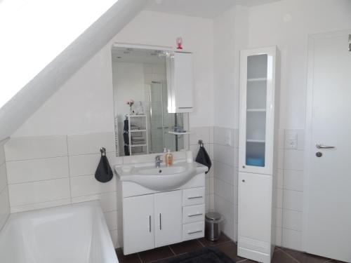 ein weißes Badezimmer mit einem Waschbecken und einem Spiegel in der Unterkunft Ferienwohnung Grünewaldstraße 22 in Bünde