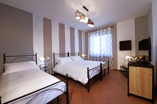a bedroom with two beds and a window at Panoramic Villa Garassino - country rooms and fine restaurant in Treiso