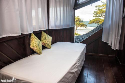 イタカレにあるPousada Hanaleiの窓のある部屋に枕が2つ置かれたベッド