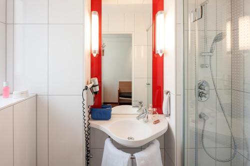 a white bathroom with a sink and a shower at ibis Nürnberg Hauptbahnhof in Nürnberg