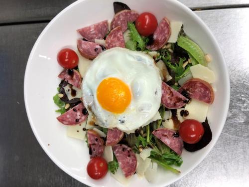 a plate of food with an egg on a salad at ibis La Bresse Gérardmer in La Bresse