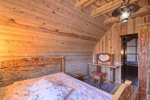 um quarto com uma cama num chalé de madeira em Sodyba "Gervinė" em Ginučiai