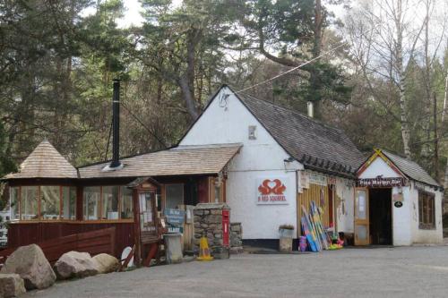 a small white building next to a building at Pine Marten Bar Glenmore Pods in Aviemore