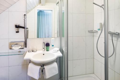 a white bathroom with a sink and a shower at Hotel Wassberg in Forch