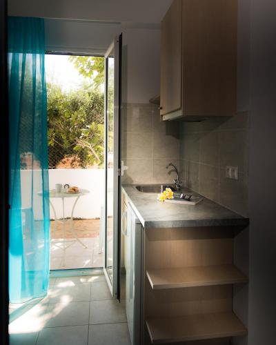 a kitchen with a sink and a sliding glass door at Ibiscus Hotel Malia in Malia