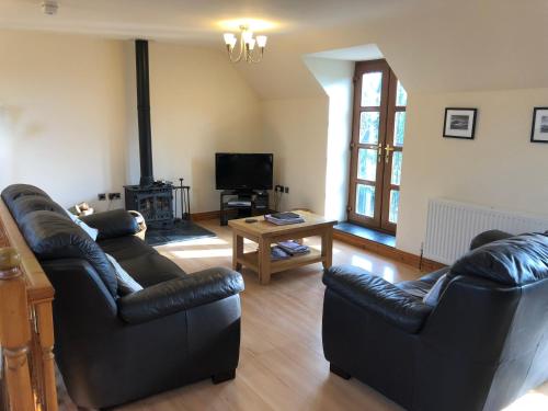 a living room with two leather couches and a tv at Hael Farm Cottage in Swansea
