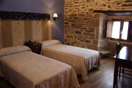 Habitación de hotel con 2 camas y pared de piedra. en Eido das Estrelas, en Valdín