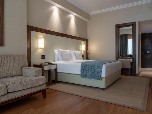 a bedroom with a bed and a chair and a couch at Stella Di Mare Dubai Marina Hotel in Dubai