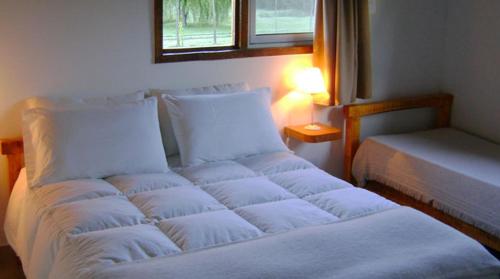 Cama blanca en habitación con ventana en Las Nubes en El Bolsón