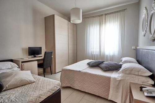 a bedroom with two beds and a desk with a computer at Rouge Hotel International in Milano Marittima