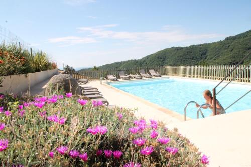 Eine Frau steht neben einem Pool mit lila Blumen. in der Unterkunft DOMAINE DU VERNADEL in Asperjoc