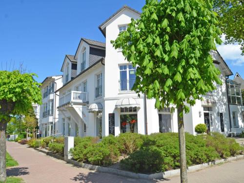 Una casa blanca con un árbol delante. en Villa Saxonia - WG 13 mit Wintergarten, strandnah en Binz