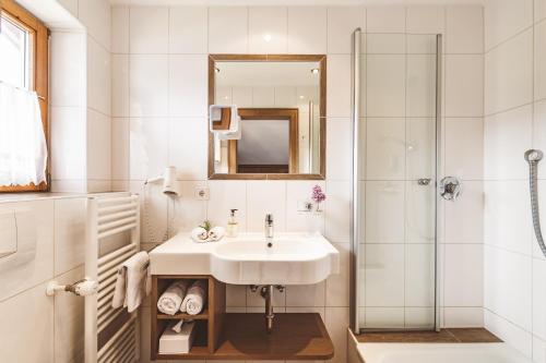 a white bathroom with a sink and a shower at Hotel Garni Gästehaus Brand in Bad Wiessee