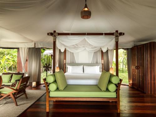a bedroom with a bed with a green couch at 9 Hornbills Tented Camp in Ko Yao Noi