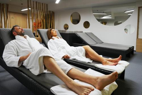 a man and woman sitting in towels on beds at San Medical Spa in Kołobrzeg
