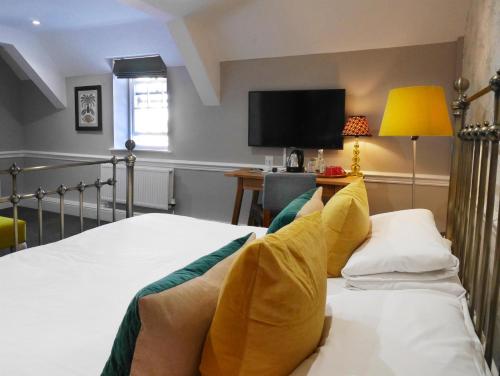 a bedroom with a bed and a tv on the wall at The Fleece in Witney
