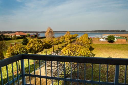 einen Balkon mit Blick auf das Wasser und die Bäume in der Unterkunft Aparthotel EuforiaPort in Pisz