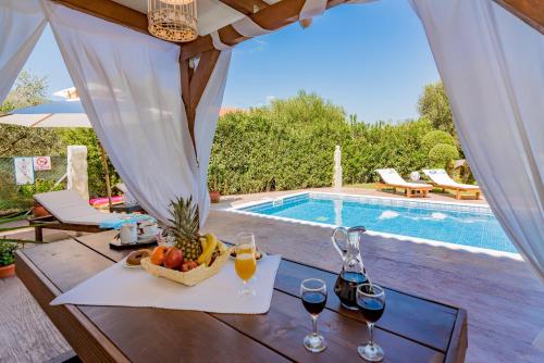 a table with wine glasses and a basket of fruit next to a pool at Villa Lina in Pandokrátor