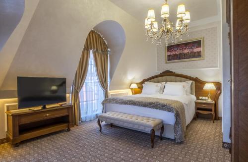 a bedroom with a bed and a television and a chandelier at Residence City Garden - Certificate of Excellence Top 10 BEST Five-Stars City Hotels for 2024 awarded by HTIF in Plovdiv