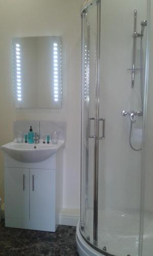 a bathroom with a glass shower and a sink at Ellesmere Hotel in Ellesmere