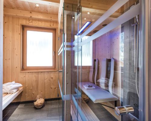 a bathroom with a shower with a bench and a window at Chalet Rudana in Sesto