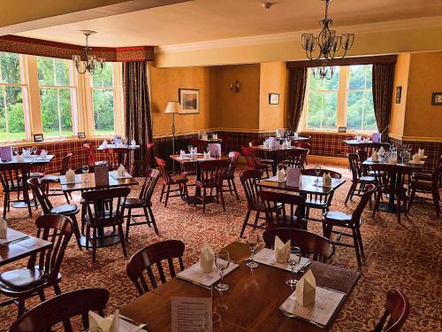 a dining room with tables and chairs and windows at Dryburgh Abbey Hotel in Melrose