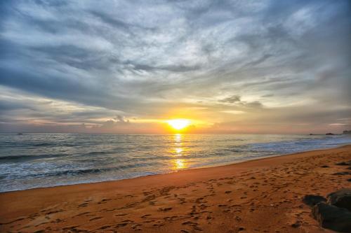 a sunset on a beach with the ocean at Indika Beach Villa in Galle