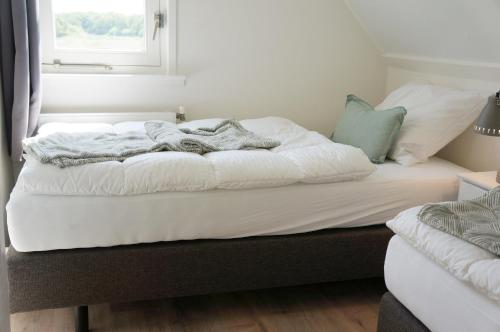 a bed with white sheets and a blanket on it at Buitenplaats Villa Deluxe in Callantsoog
