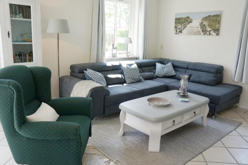 a living room with a blue couch and two chairs at Buitenplaats Villa Deluxe in Callantsoog