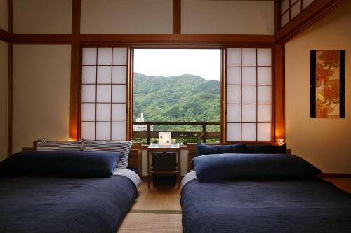 a room with two beds in front of a window at Taisho Modern Villa Zen in Hakone